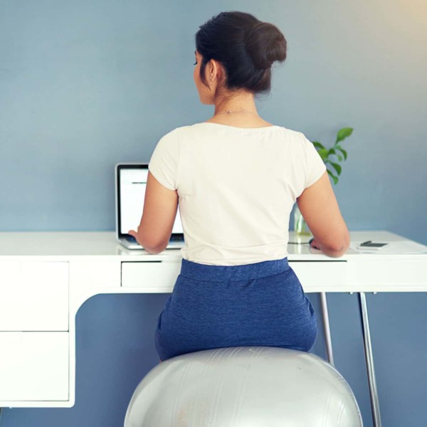 Image of someone sitting on a medicine ball chair at their desk.