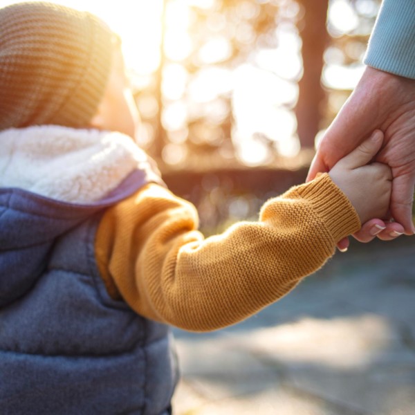 small child holding the hand of an adult