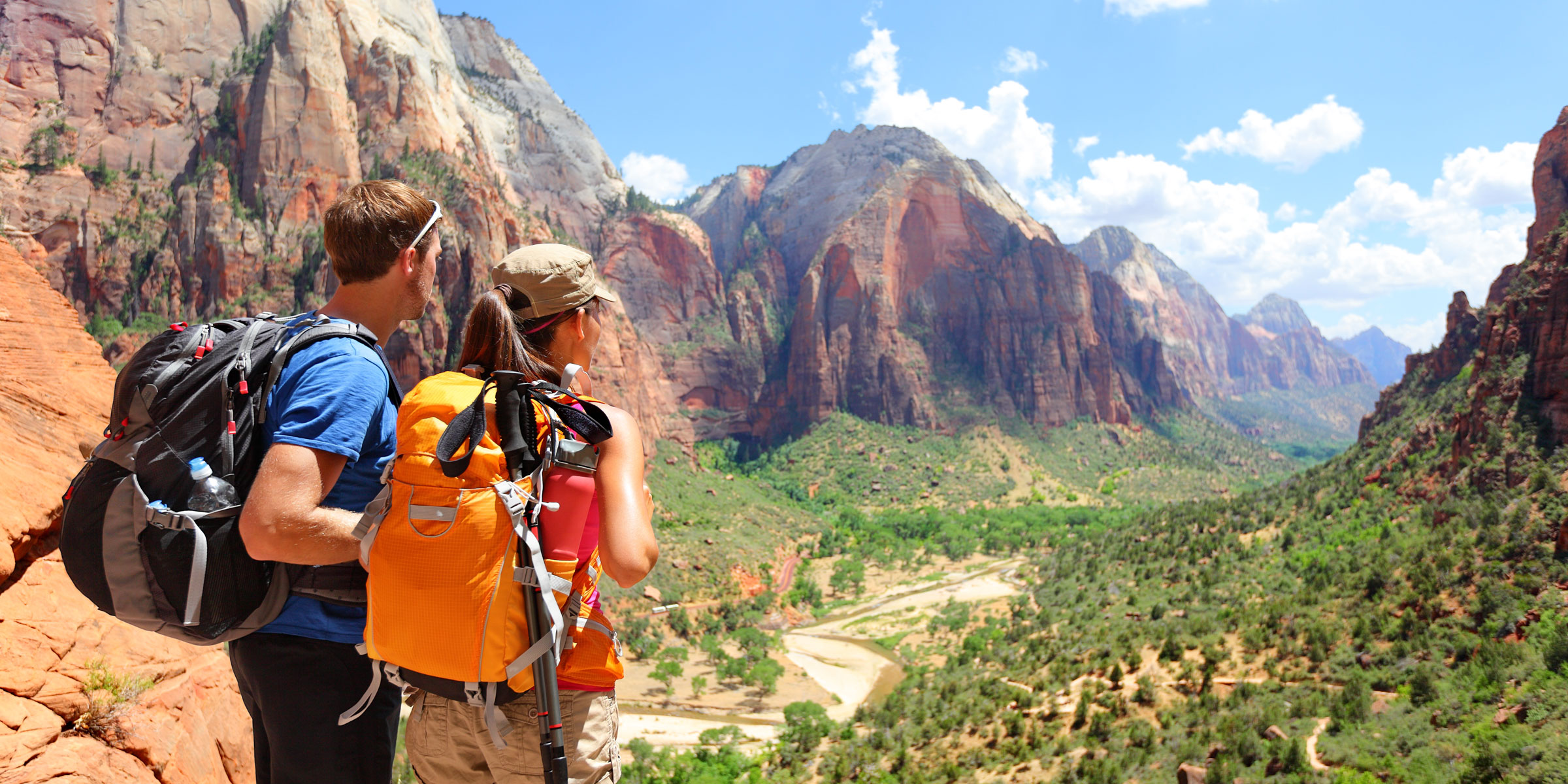 couple hiking through a sunny valley surrounded by mountains