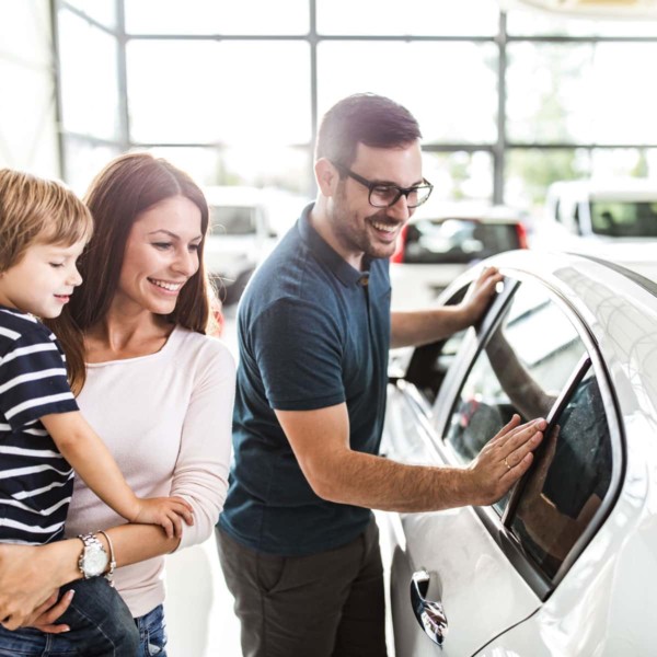 Image of people looking at a car in a dealership.