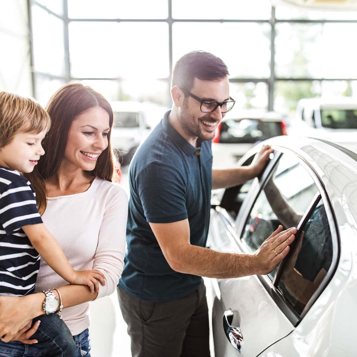 Image of people looking at a car in a dealership.