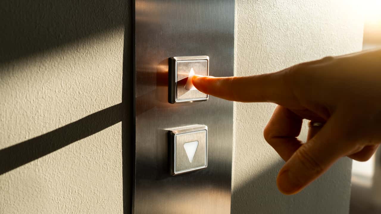 Image of someone pushing elevator buttons.