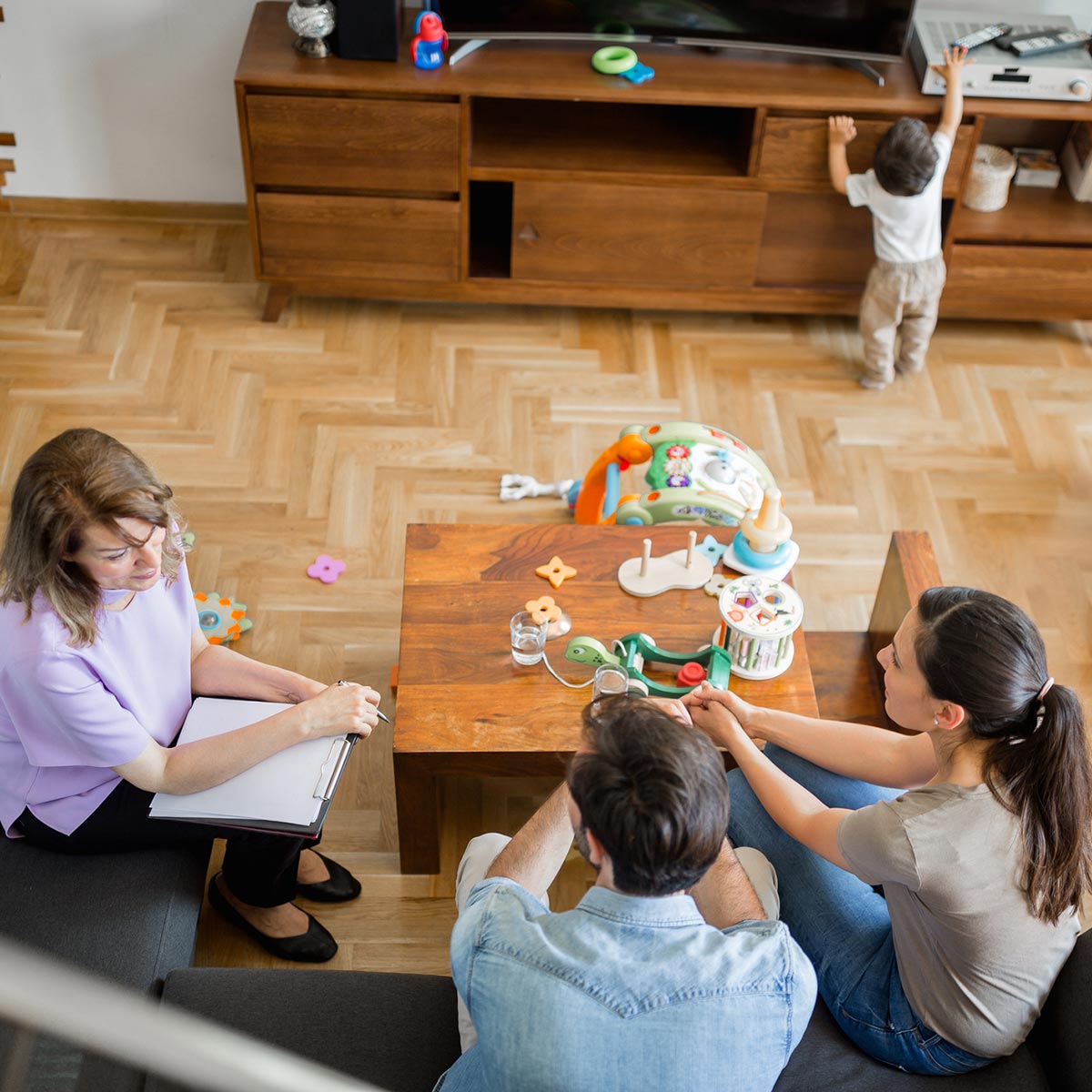 family talking while kid plays with toys and reaches for a remote