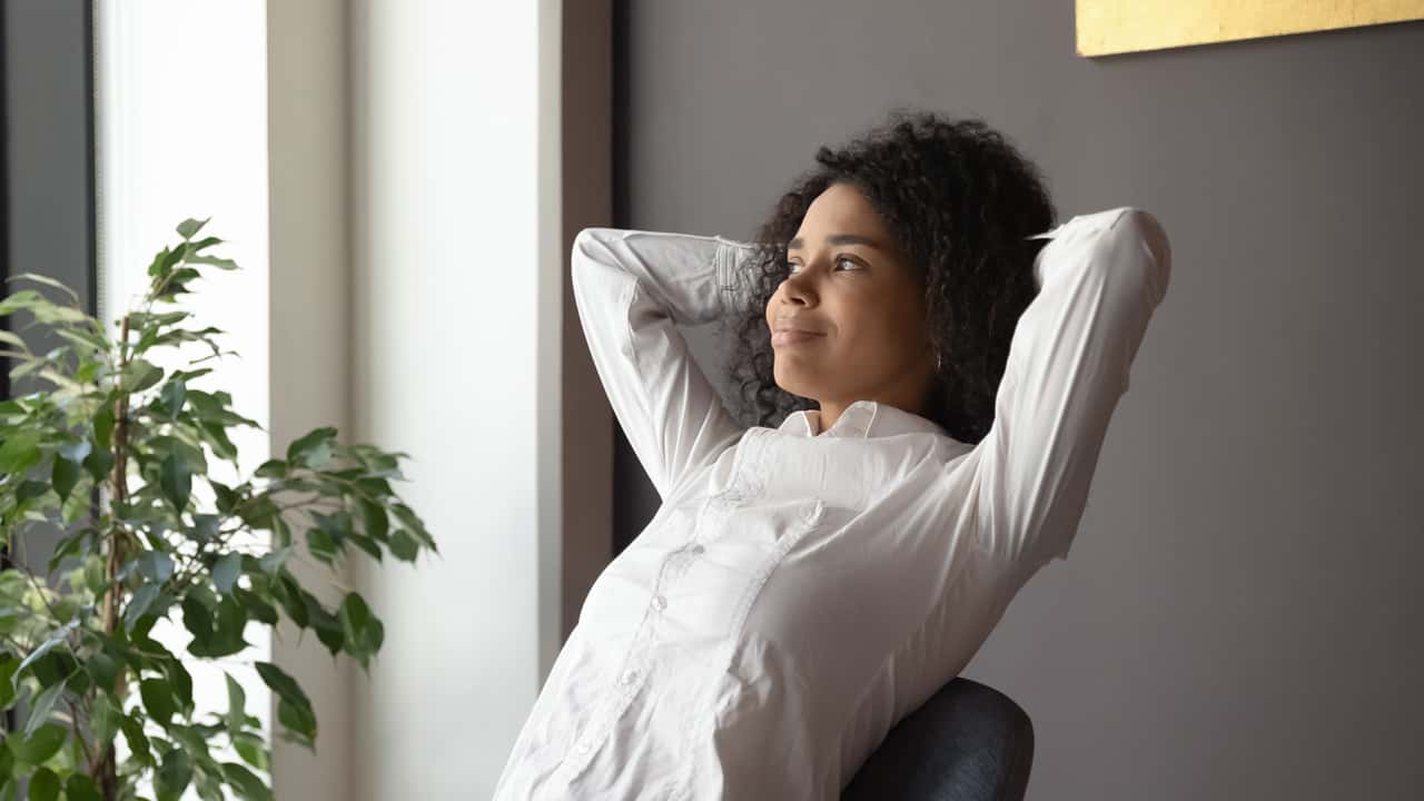 Image of someone with their hands behind their head.