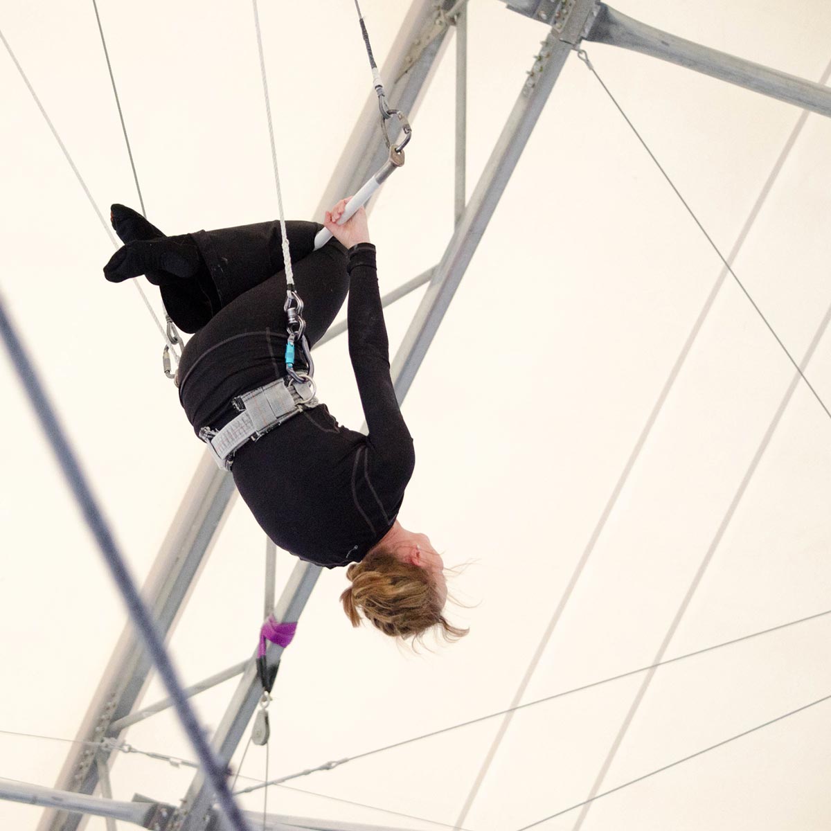 Image of someone swinging from a bar in air.