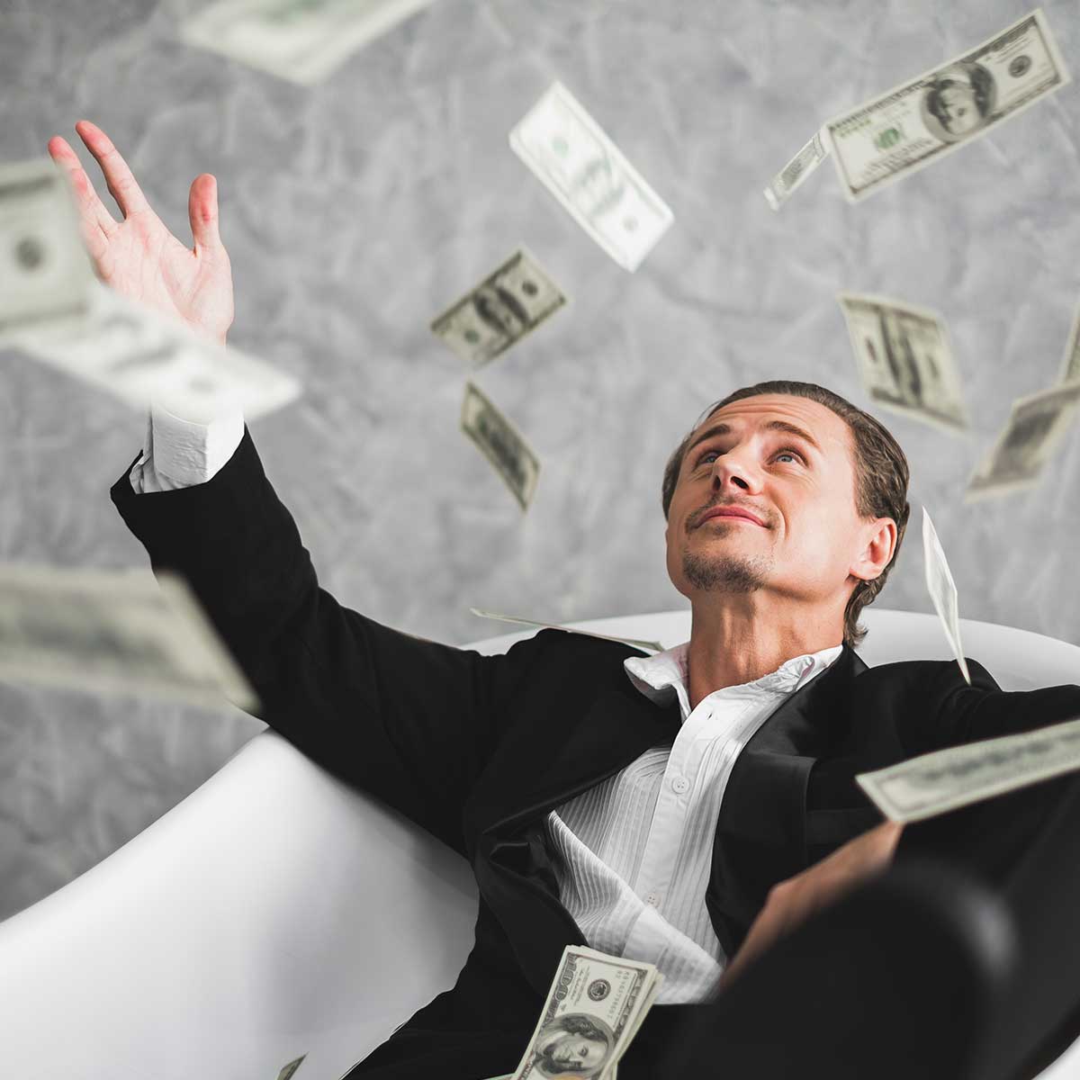 man sitting in a car throwing money in the air