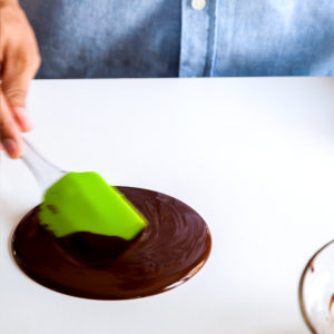 Moving liquid chocolate on the table with a spatula
