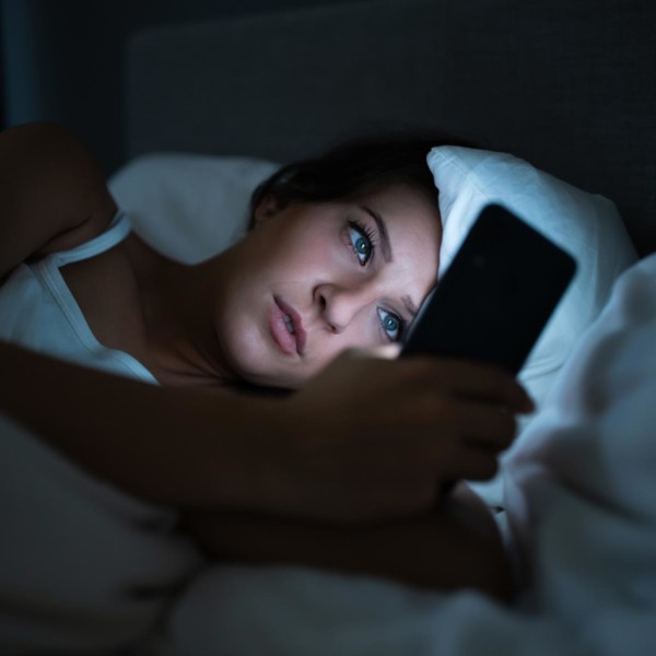 Image of someone on their phone while laying in bed.