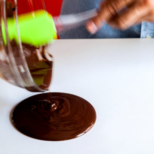 Pouring liquid chocolate on the table with a spatula