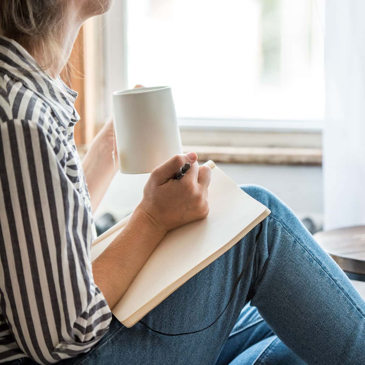 person drinking tea and journaling to relax
