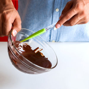 Tilting the liquid chocolate so that it pours onto the table