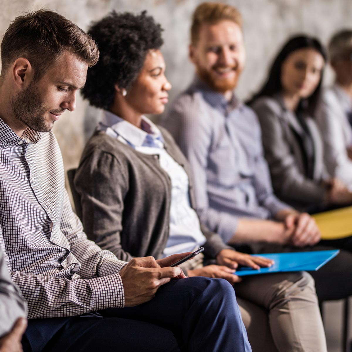 a group of people sitting and waiting for a job interview