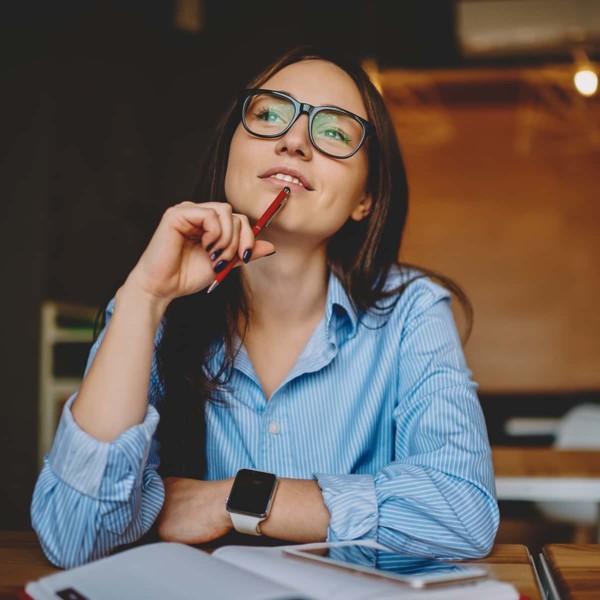 Woman thinking about being self aware with pen in hand