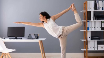Image of someone doing a yoga pose at their computer desk.