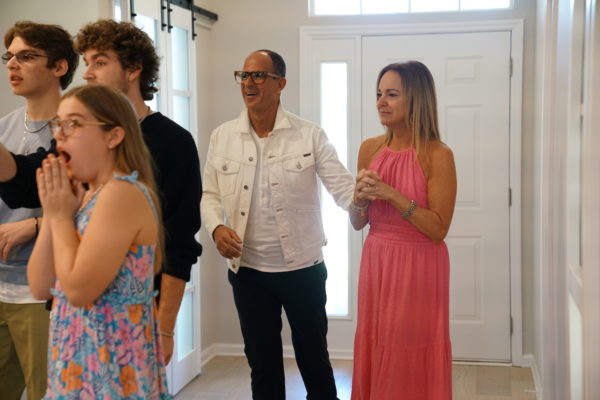A family walking into a renovated house with Marcus Lemonis