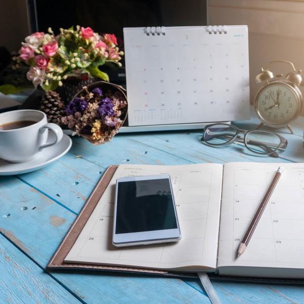 Phone, calendar and a planner on a desk of someone planning to hangout with their friends