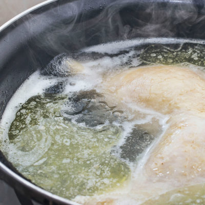 Boiling chicken in tall pot for chicken and rice dish