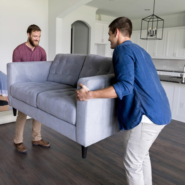 Friend giving his friend a hand moving a couch