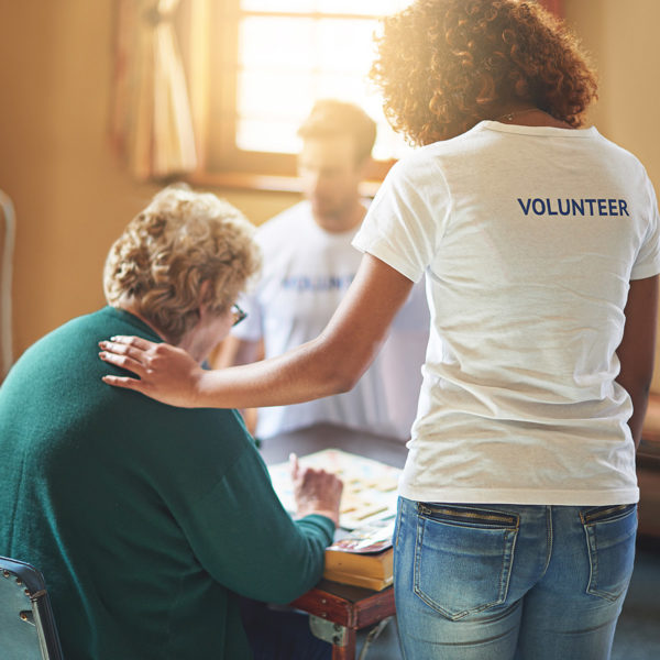 A volunteer is giving support to an elderly lady by donating her time
