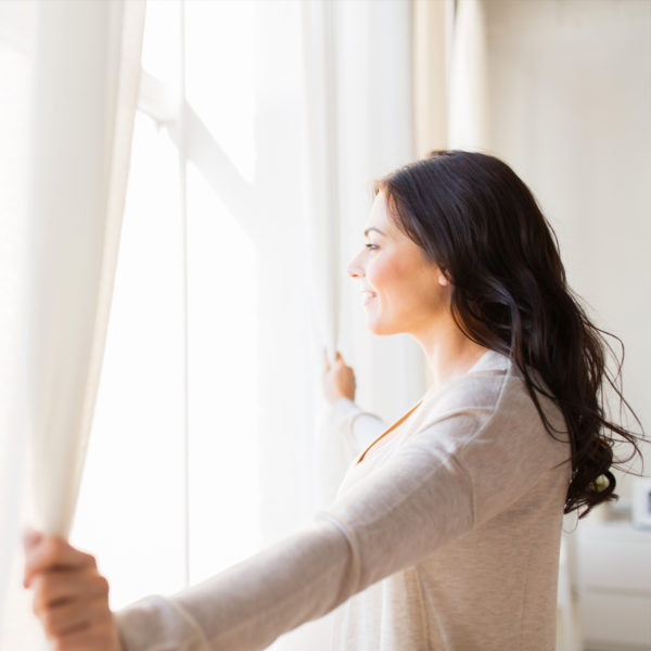 Woman opening up curtains to get ready for work from home